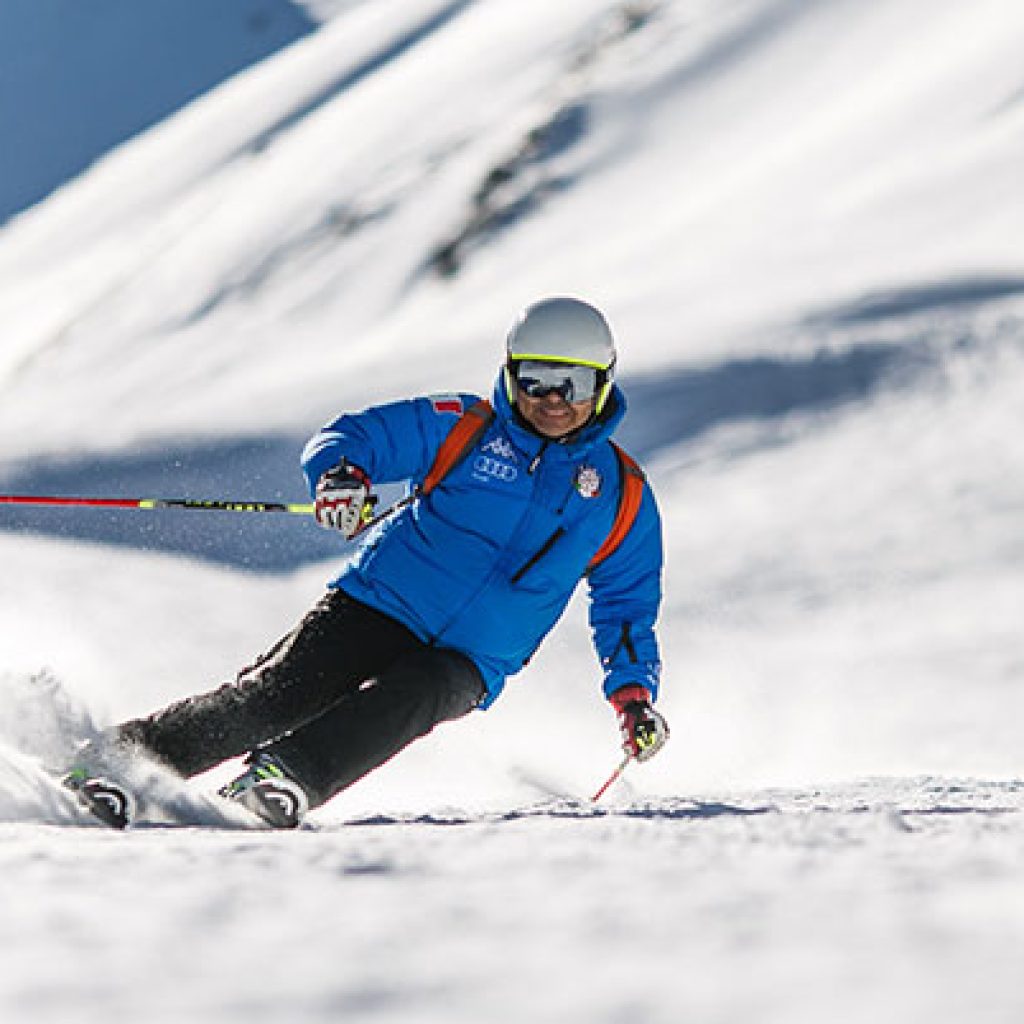 Skier carving snowy slope in blue jacket