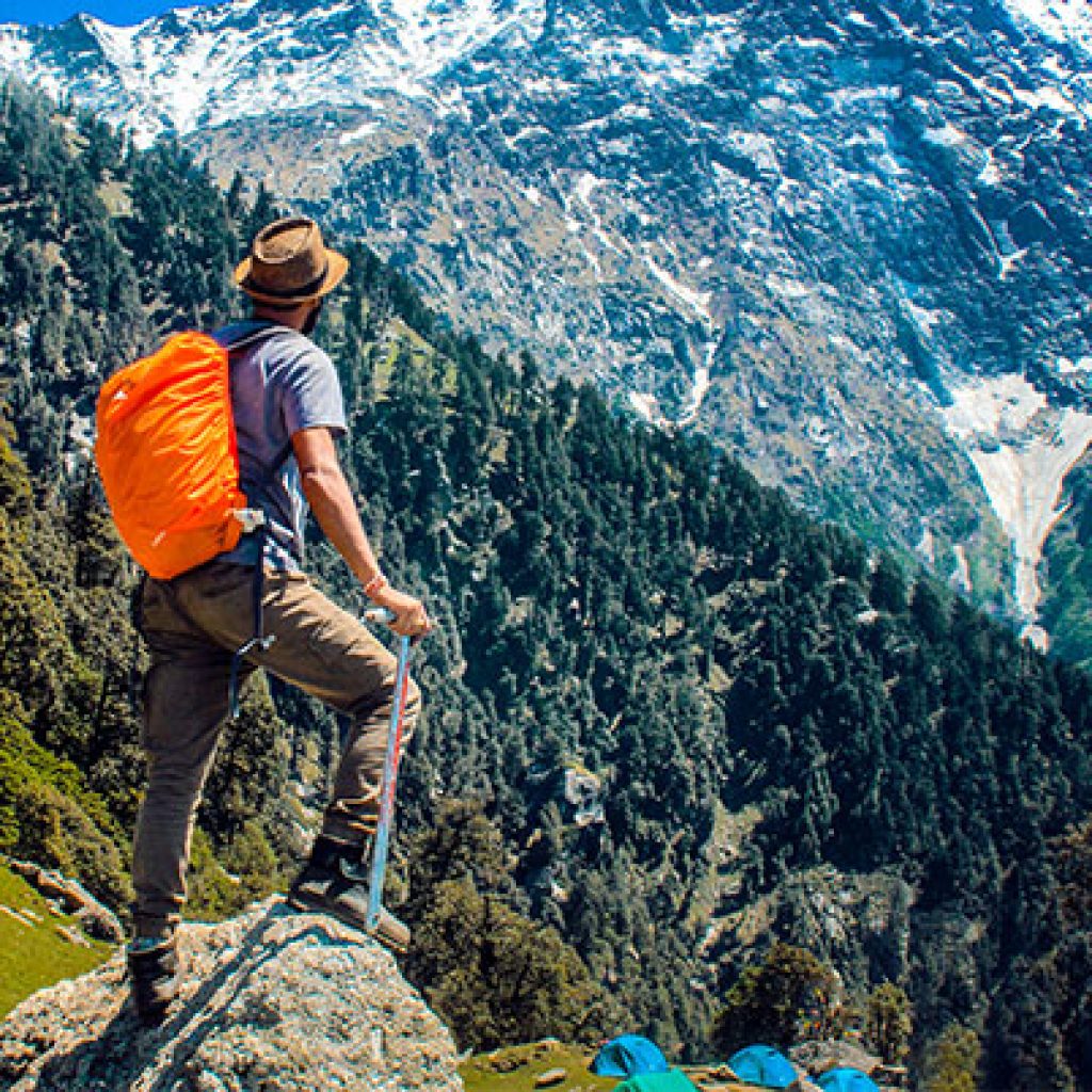 Hiker with orange backpack overlooking snowy mountain valley